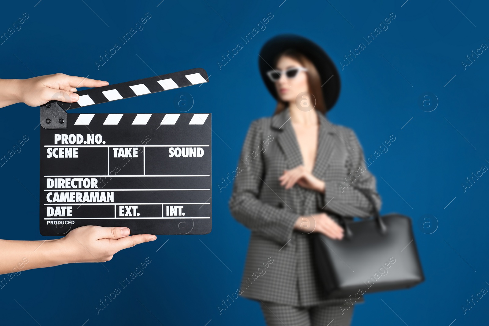 Image of Assistant holding clapperboard and beautiful young woman on blue background, closeup. Cinema production 