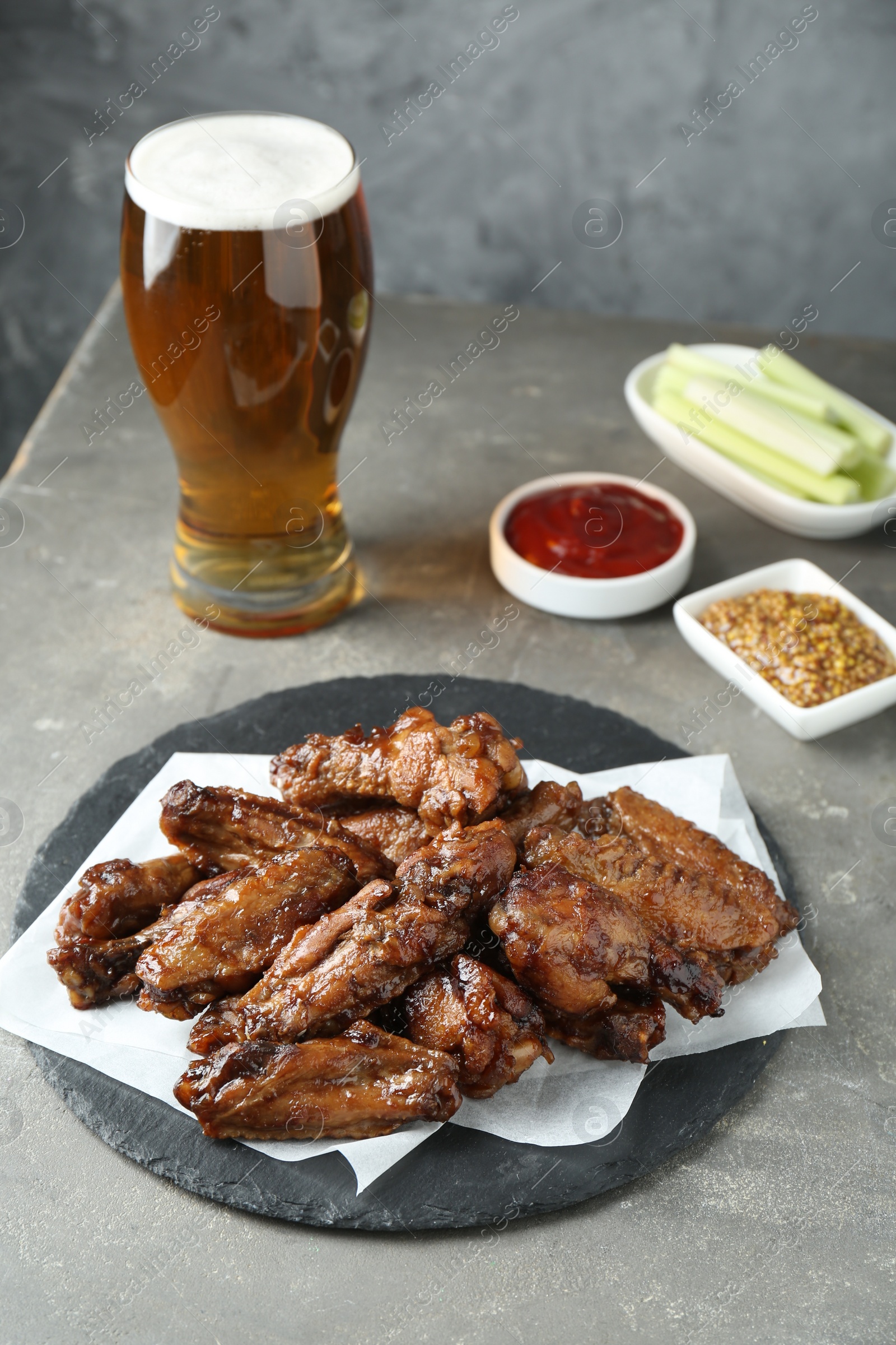 Delicious chicken wings served with beer on grey table Photo of Delicious chicken wings served with beer on grey table