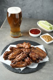 Photo of Delicious chicken wings served with beer on grey table
