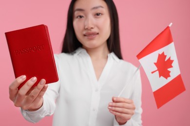 Photo of Immigration to Canada. Happy woman with passport and flag on pink background, selective focus