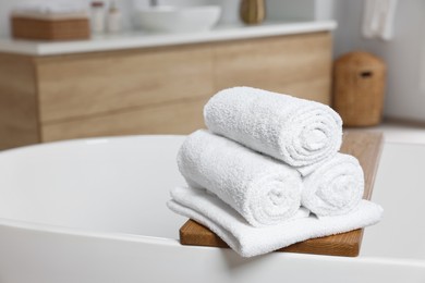 Photo of Rolled white towels on tub in bathroom. Space for text
