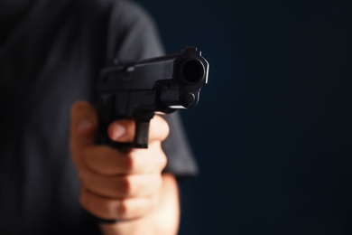 Photo of Man holding gun on dark background, closeup