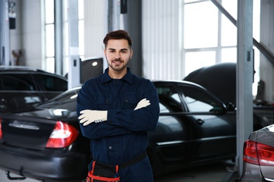 Photo of Portrait of technician near car at automobile repair shop