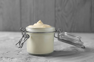 Photo of Tasty mayonnaise in jar on gray textured table, closeup