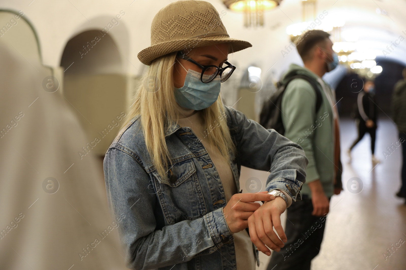 Photo of Young woman in protective mask waiting for train at subway station. Public transport