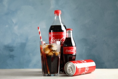 MYKOLAIV, UKRAINE - NOVEMBER 15, 2018: Bottles, glass and can with Coca Cola on table against color background