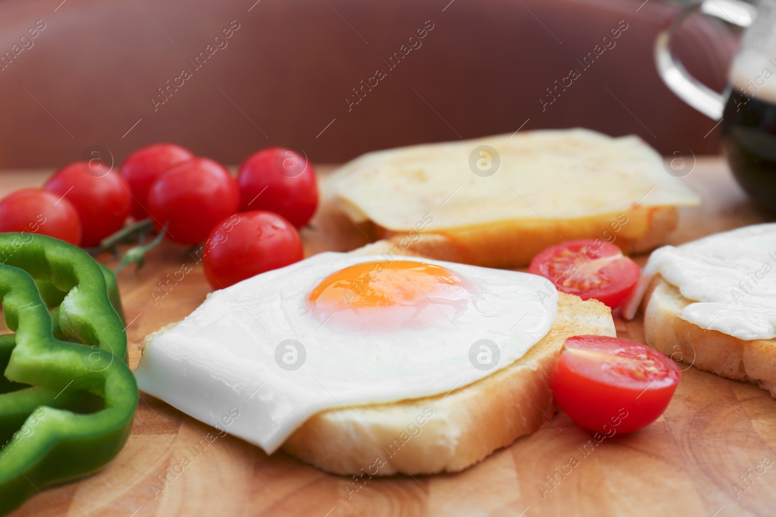 Photo of Tasty toasts with fried egg, cheese and vegetables on wooden board, closeup