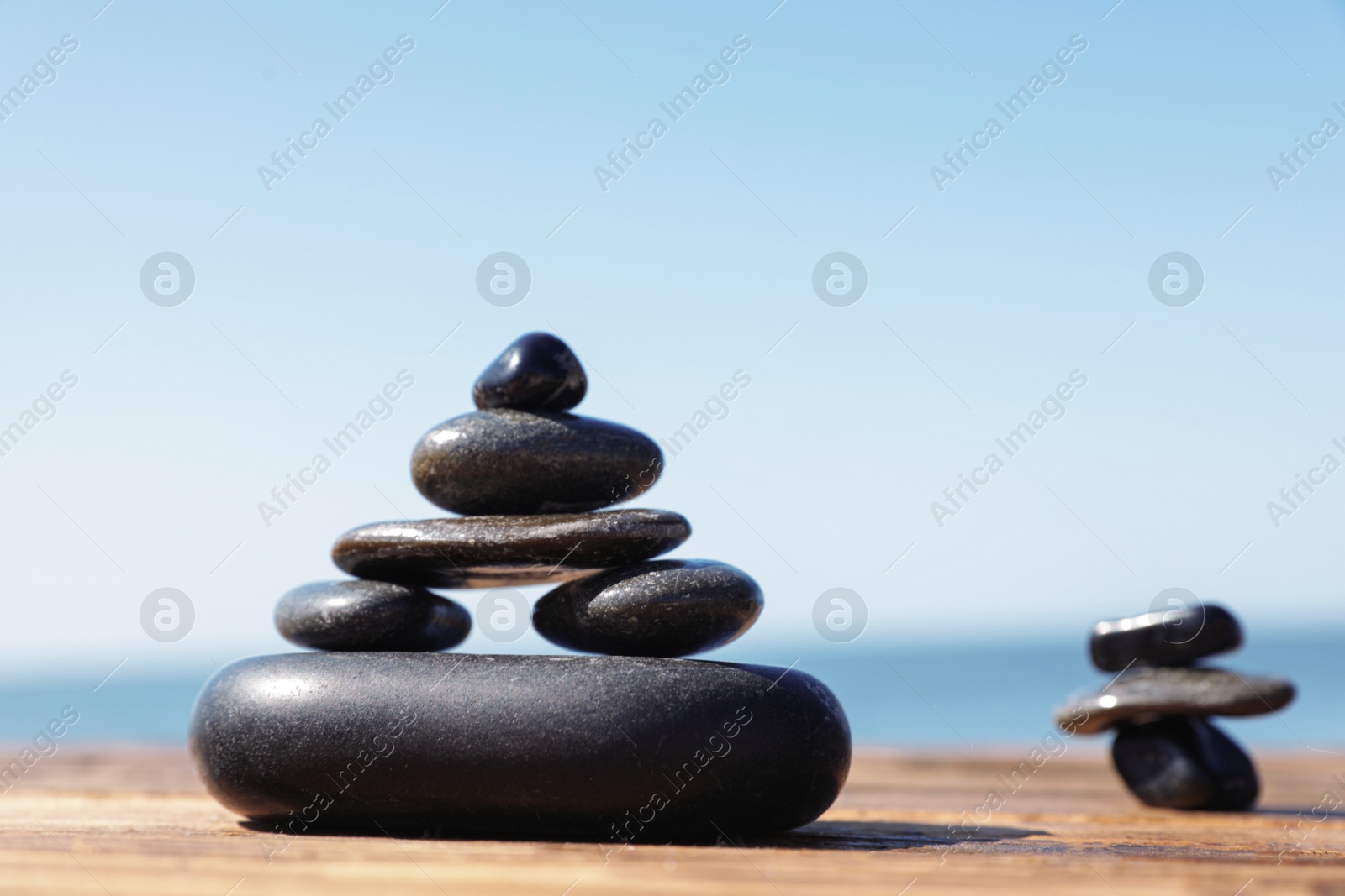 Photo of Stacks of stones on wooden pier near sea, space for text. Zen concept