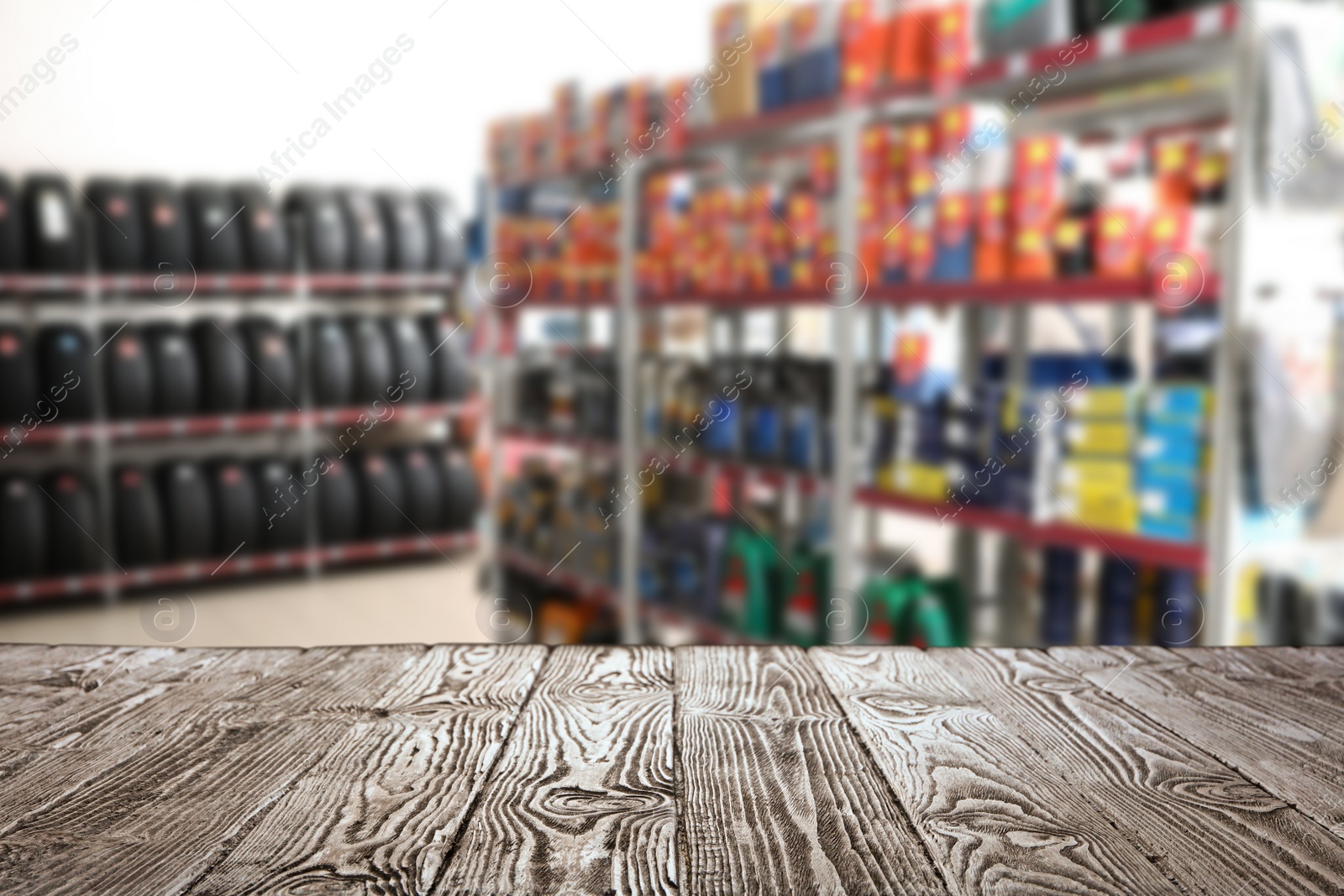 Image of Empty wooden surface and blurred view of car tires in auto store, closeup. Space for text 