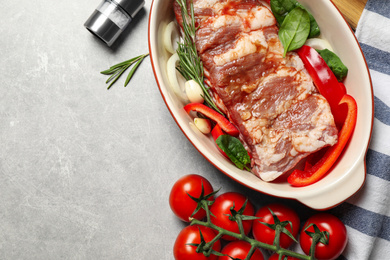 Photo of Raw spare ribs with garnish on light table, flat lay. Space for text
