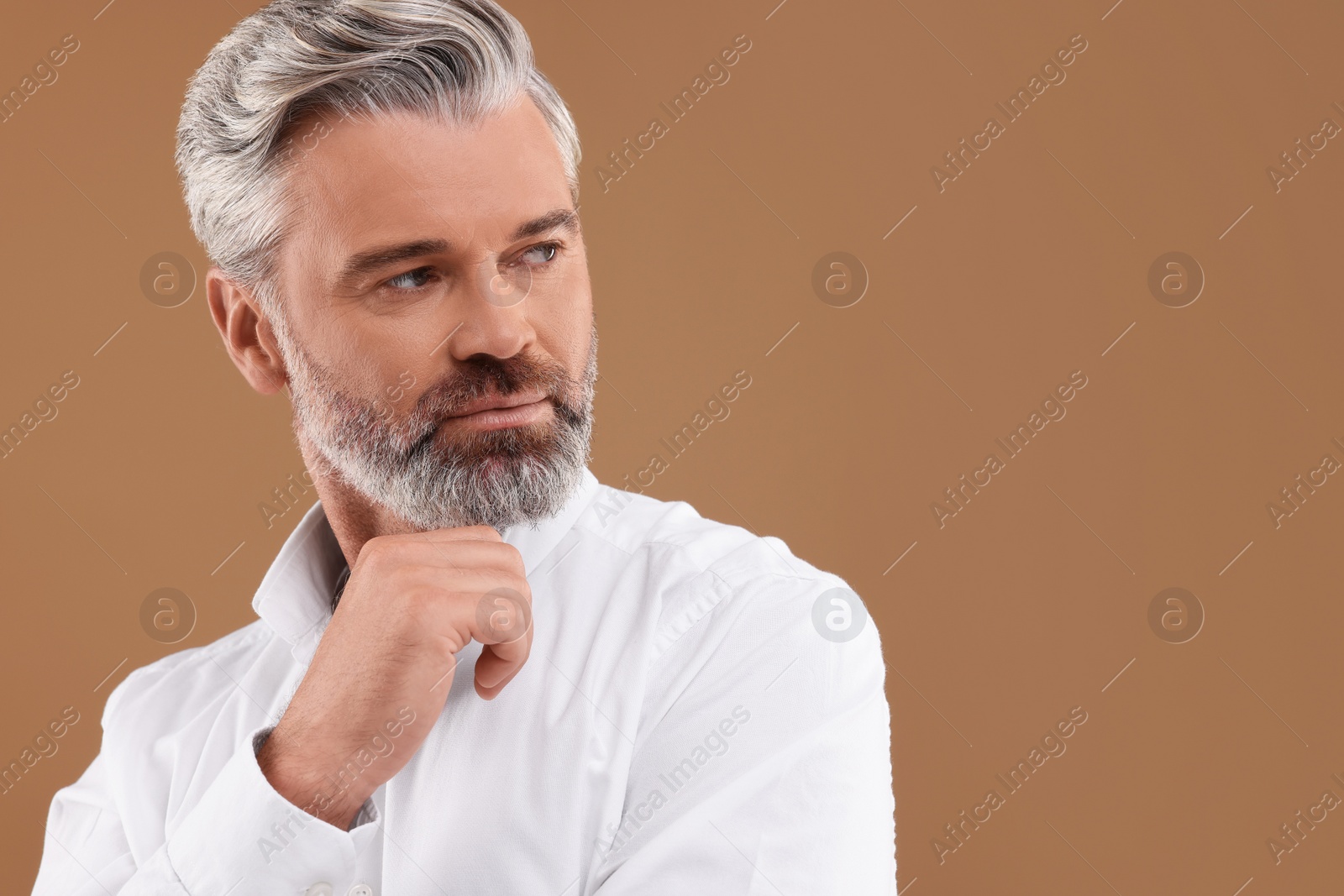 Photo of Portrait of confident man with beautiful hairstyle on light brown background. Space for text