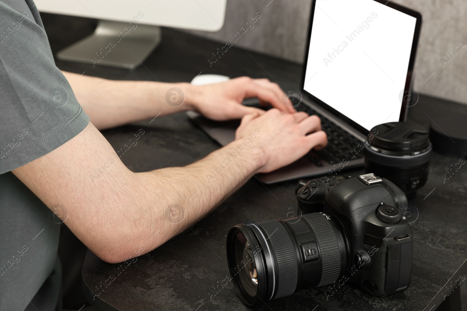 Photo of Photographer using laptop at dark table with camera, closeup