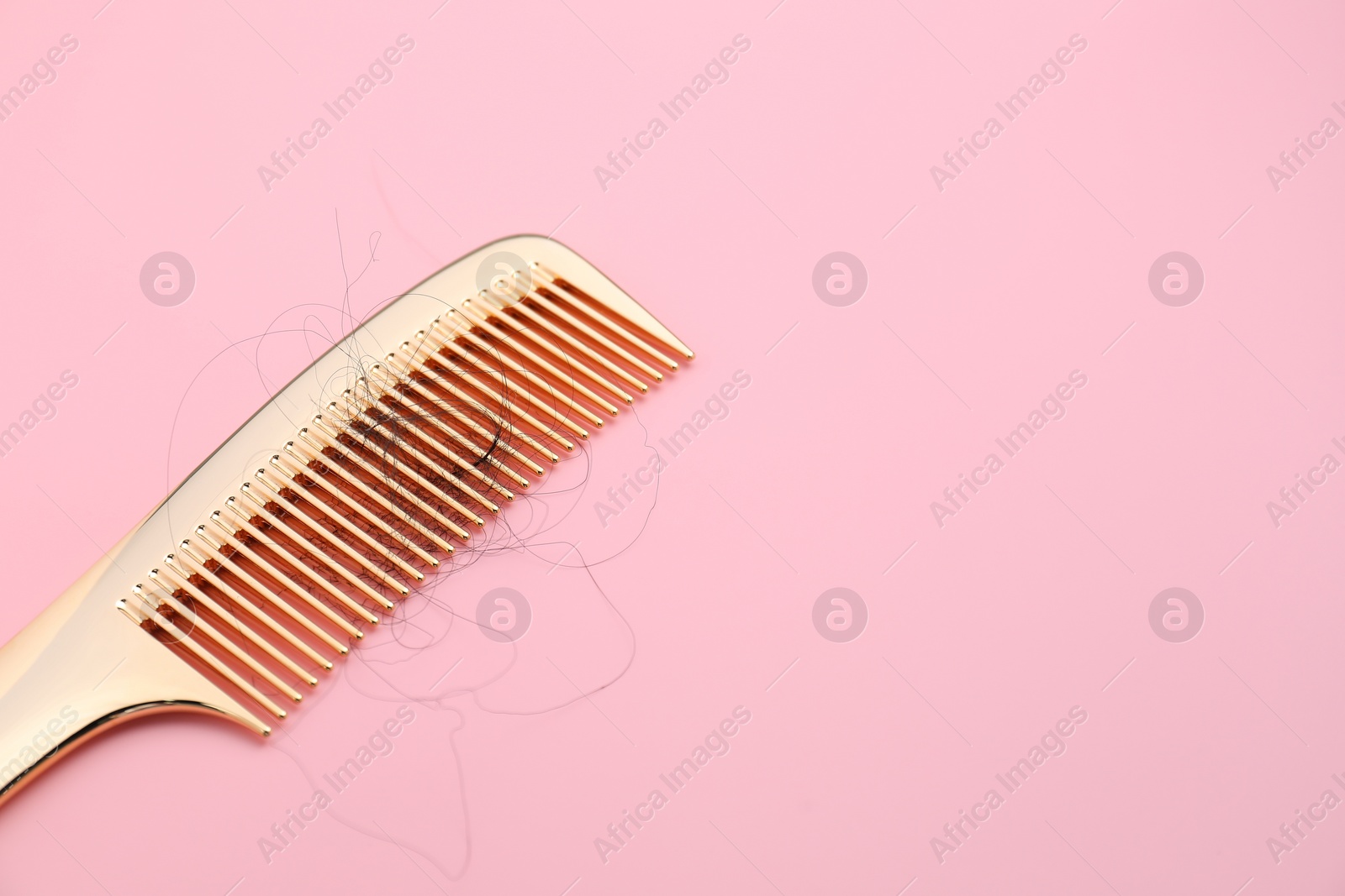 Photo of Comb with lost hair on pink background, space for text