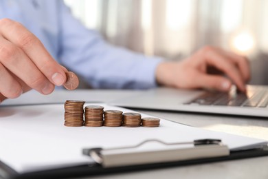 Photo of Man stacking coins at table indoors, closeup