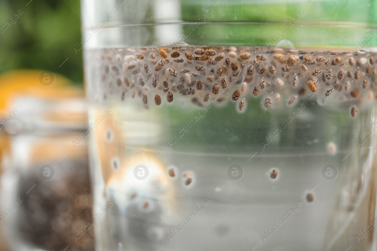 Photo of Glass of water with chia seeds on blurred background, closeup