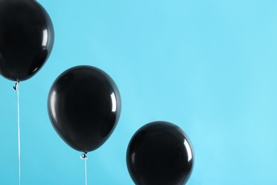 Photo of Black balloons on blue background, space for text. Halloween party