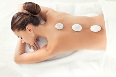 Young woman with stones on her back in spa salon