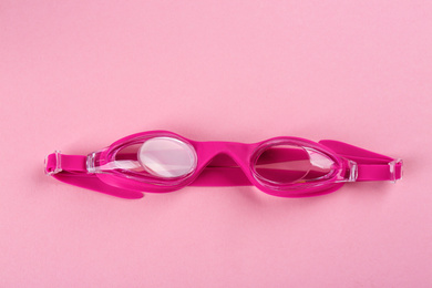 Photo of Swimming goggles on pink background, top view