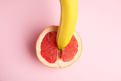 Photo of Fresh grapefruit and banana on pink background, top view. Sex concept