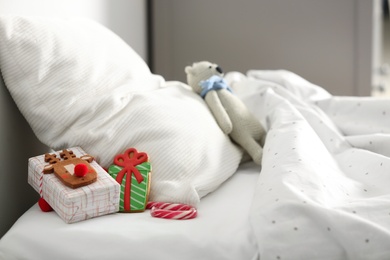 Photo of Gift box with candy cane and gingerbread on bed in children's room. St. Nicholas Day tradition