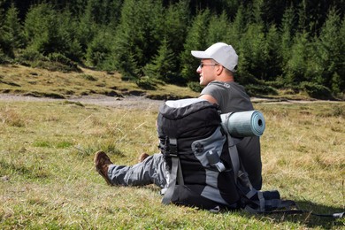 Man with backpack and sleeping mat near forest