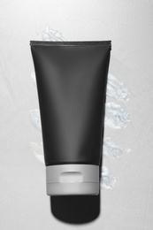 Photo of Black tube with men's cosmetic product on grey background, top view