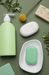 Photo of Soap bars and bottle dispenser on green background, flat lay