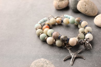 Photo of Beautiful bracelets with gemstones on grey background, closeup. Space for text