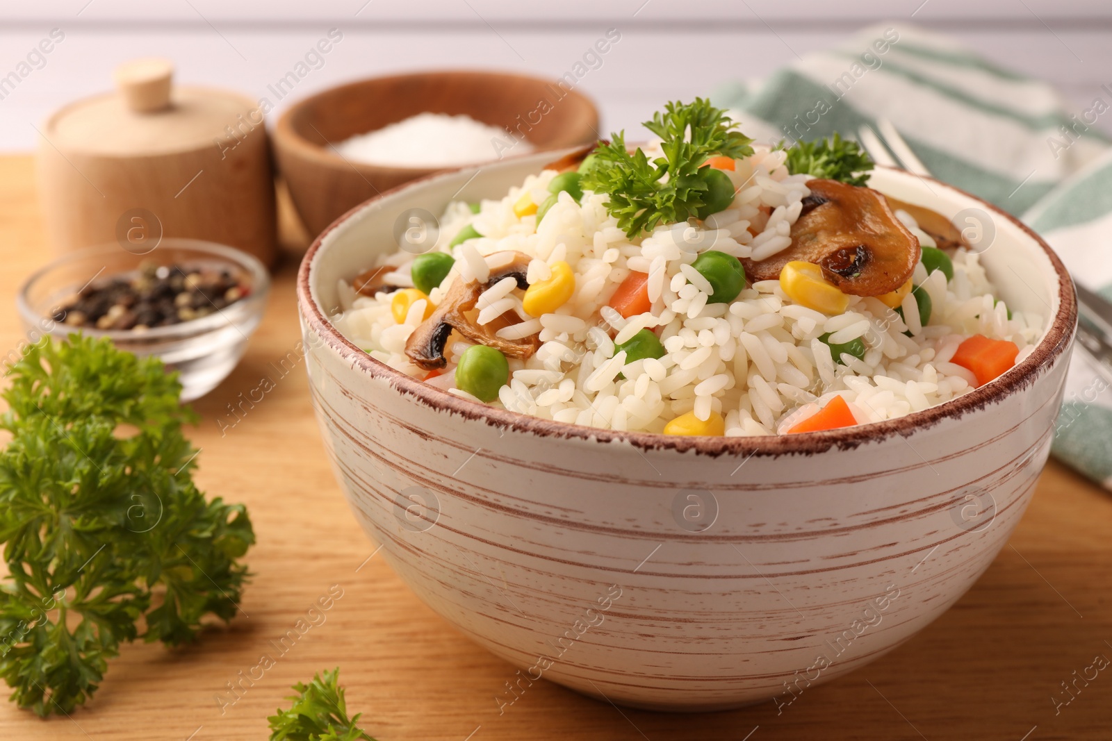 Photo of Bowl of delicious rice with vegetables on wooden table, closeup