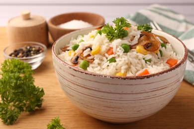 Bowl of delicious rice with vegetables on wooden table, closeup