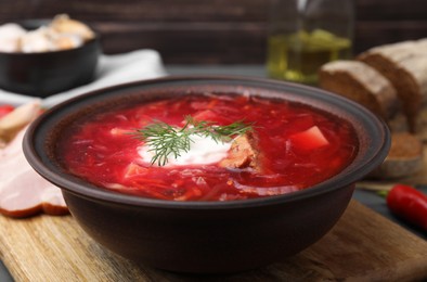 Photo of Tasty borscht with sour cream in bowl on grey table, closeup