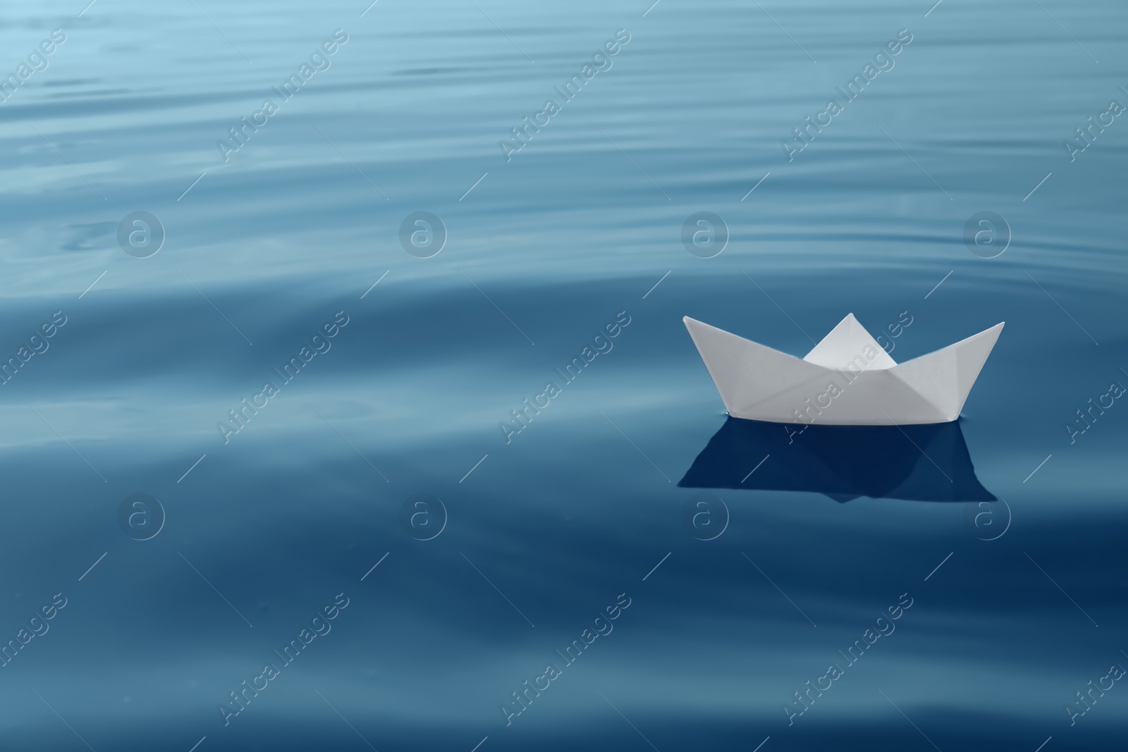 Photo of White paper boat floating on river, space for text