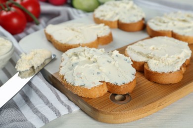 Photo of Toasted bread with cream cheese on white wooden table, closeup