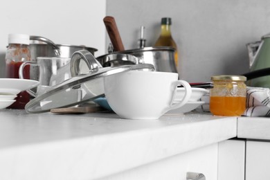 Photo of Many dirty utensils and dishware on countertop in messy kitchen, closeup