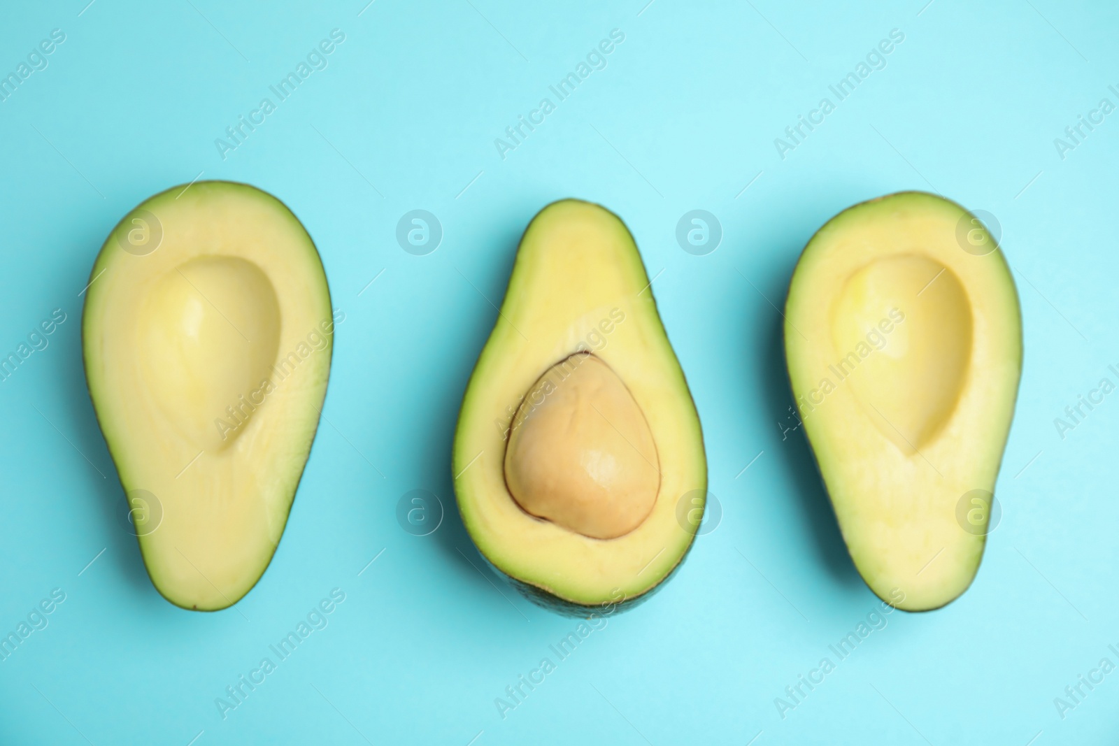 Photo of Cut fresh ripe avocados on blue background, flat lay