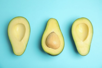 Cut fresh ripe avocados on blue background, flat lay