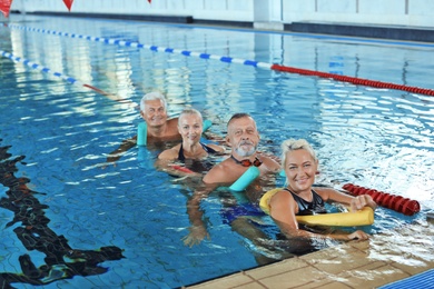 Photo of Sportive senior people doing exercises in indoor swimming pool