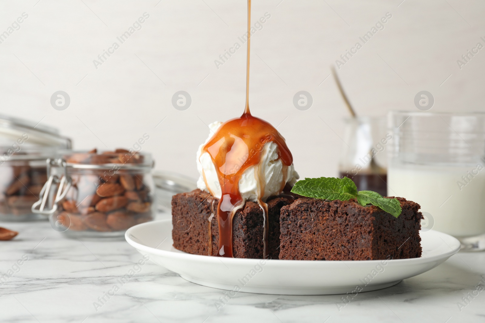 Photo of Pouring sauce onto ice-cream with fresh brownies on plate, space for text. Delicious chocolate pie