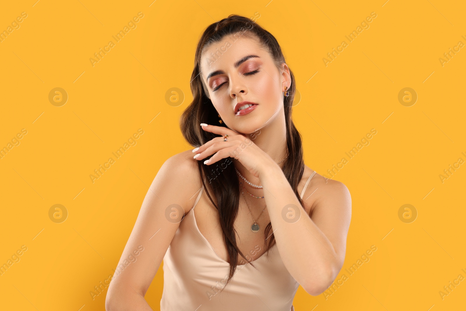 Photo of Beautiful woman with elegant jewelry on orange background