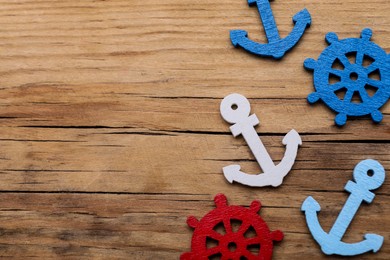 Photo of Anchor and ship wheel figures on wooden table, flat lay. Space for text