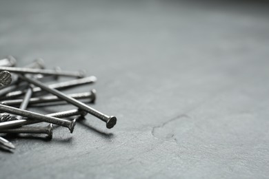 Photo of Many metal nails on grey background. Space for text