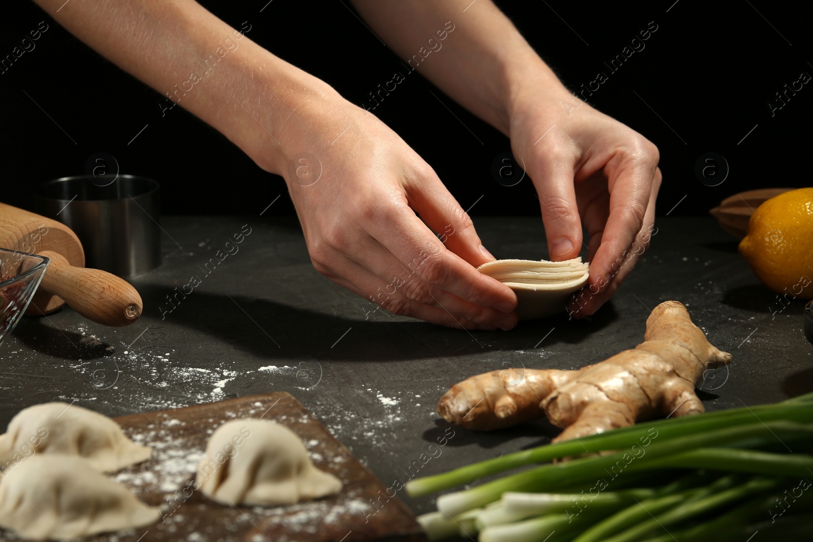 Photo of Woman making gyoza at grey table, closeup