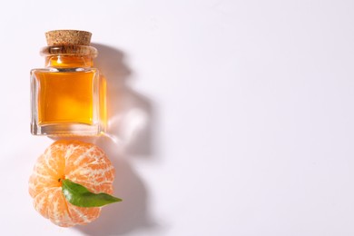 Aromatic tangerine essential oil in bottle and citrus fruit on white table, top view. Space for text