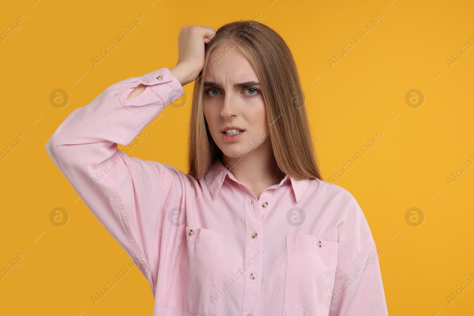 Photo of Portrait of embarrassed young woman on orange background