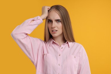 Photo of Portrait of embarrassed young woman on orange background