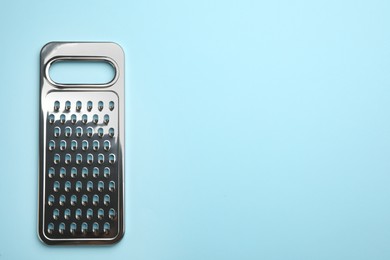 Modern grater on light blue background, top view. Space for text