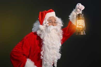 Photo of Merry Christmas. Santa Claus with vintage lantern on dark background
