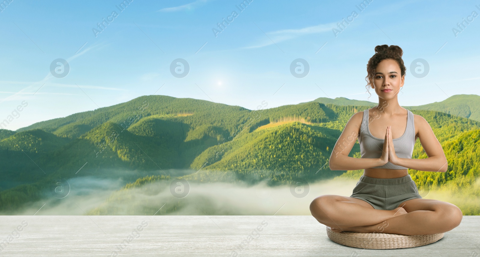 Image of Young African American woman practicing yoga on wooden surface against beautiful mountain landscape, space for text. Banner design