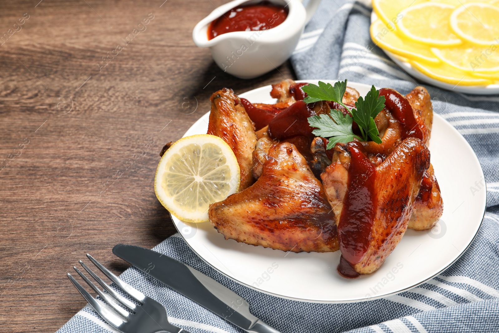 Photo of Delicious fried chicken wings served on wooden table, space for text