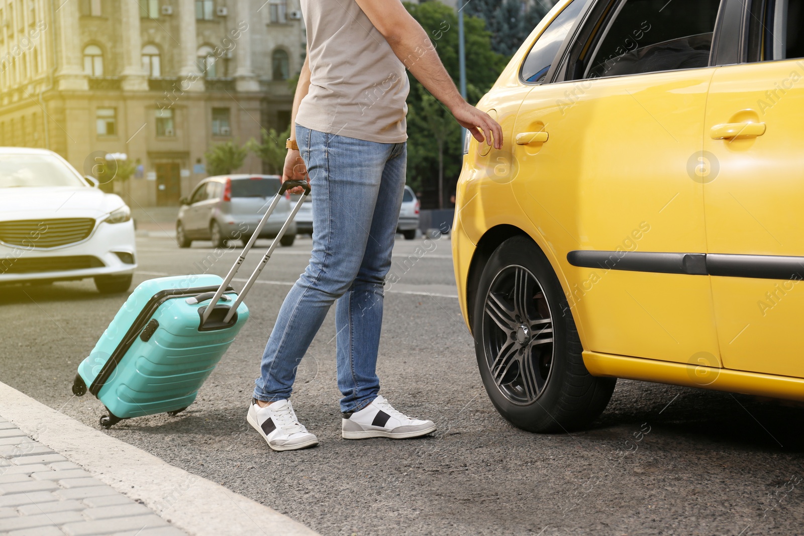 Photo of Man with suitcase getting into taxi on city street